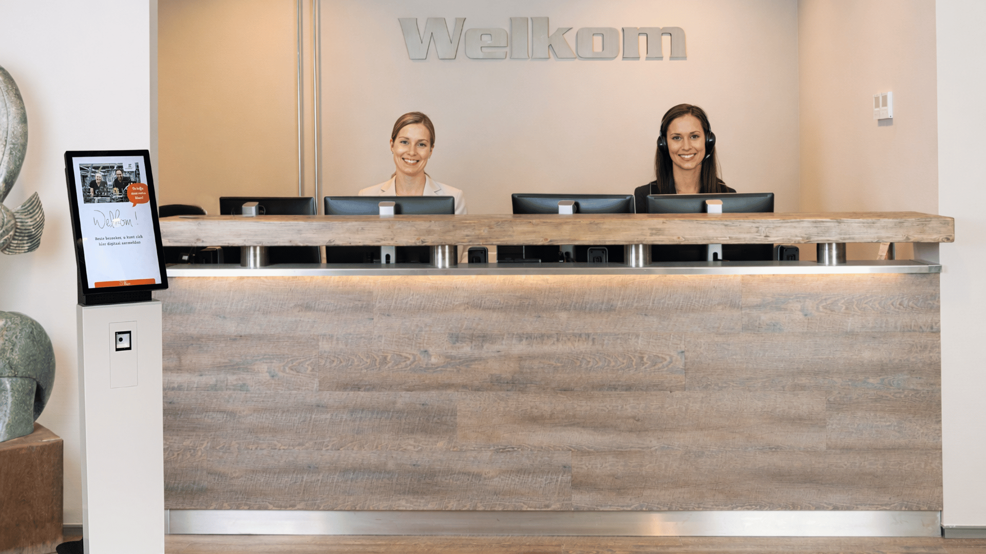 Woman at reception, equiped with EVA Bezoekers Registratie.